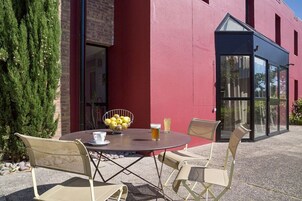 Un área de estar al aire libre con una mesa redonda y cuatro sillas, un bol de limones y dos bebidas.