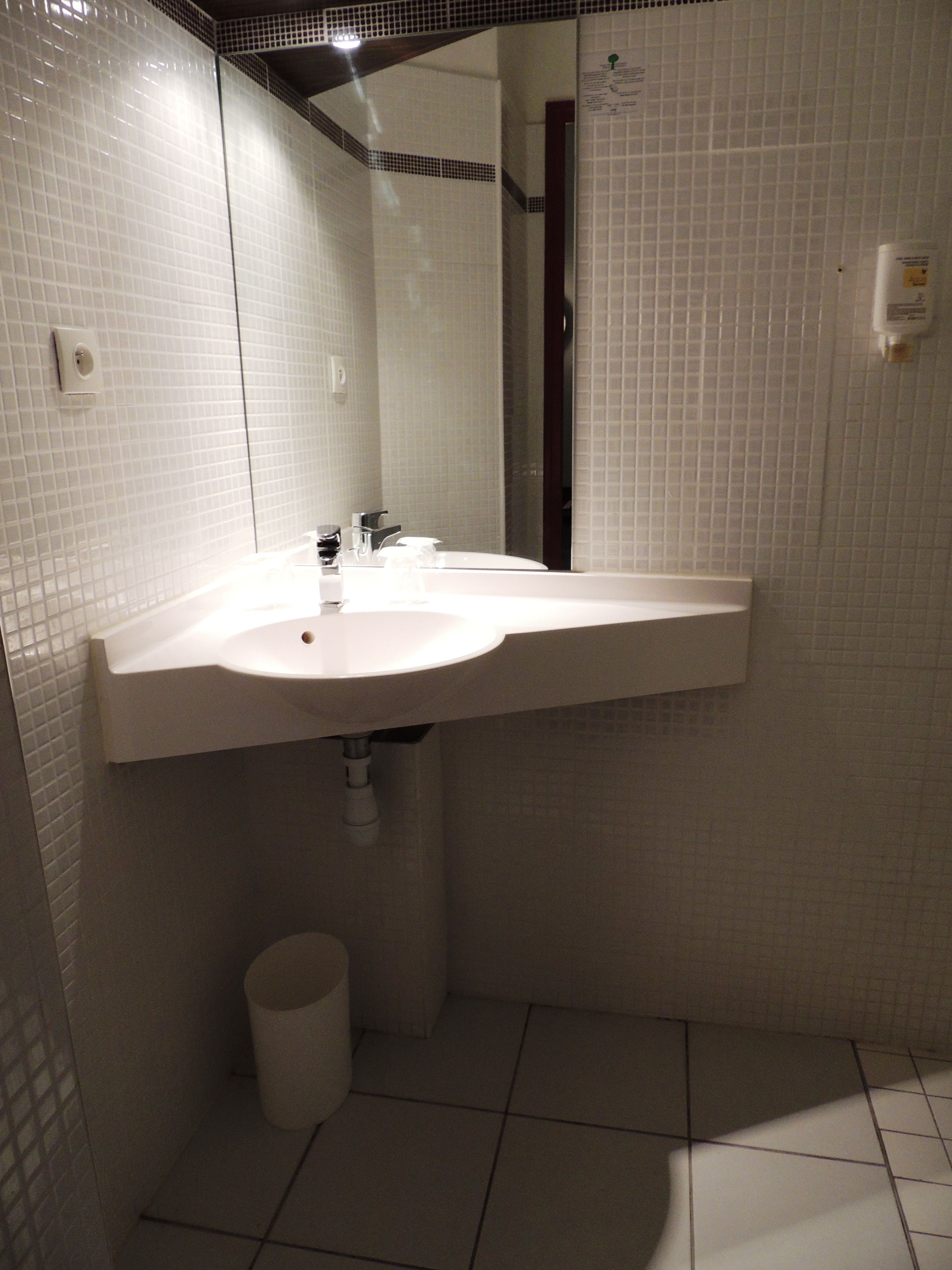 A bathroom with a white sink, mirror, and tiled walls.