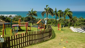 A playground with swings and climbing structures, a fenced area, and a chessboard. - First Group Chaka Rock Chalets (Ballito)