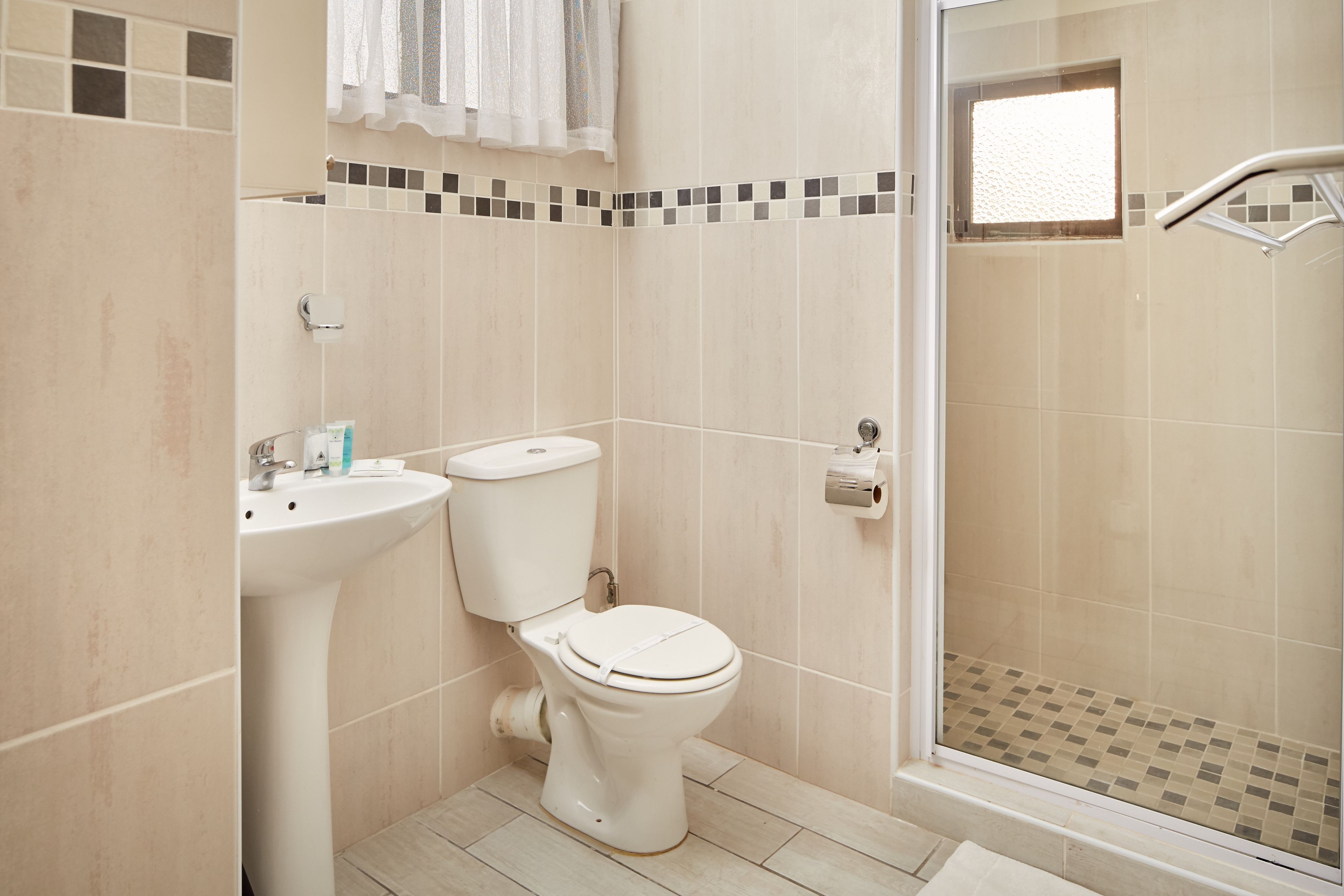 Une salle de bain comprenant des toilettes, un lavabo et un espace douche.