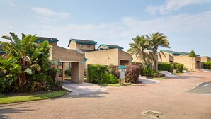 A residential area with brick houses, palm trees, and a paved driveway. - First Group Club Hacienda (Margate)