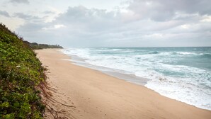 A beach with waves crashing onto the shore, a clear sky, and a distant shoreline. - First Group Club Hacienda (Margate)