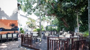 An outdoor patio area with tables and chairs, surrounded by greenery and a mural on the wall. - First Group Lake View Cabanas (St. Lucia)