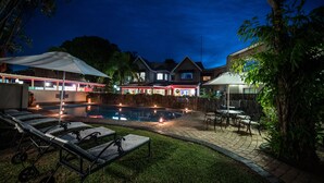 A nighttime outdoor pool area with lounge chairs, a small pool, and surrounding vegetation. - First Group Lake View Cabanas (St. Lucia)