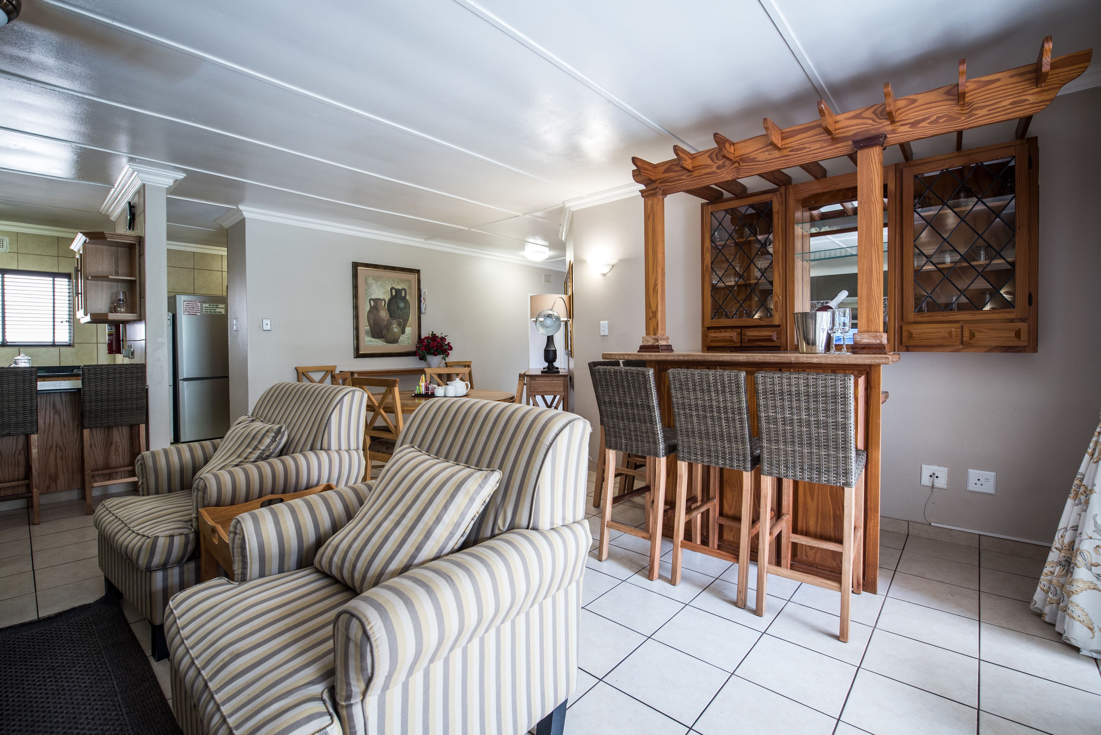 A living room with striped sofas, a wooden coffee table, and a dining area with wicker chairs.