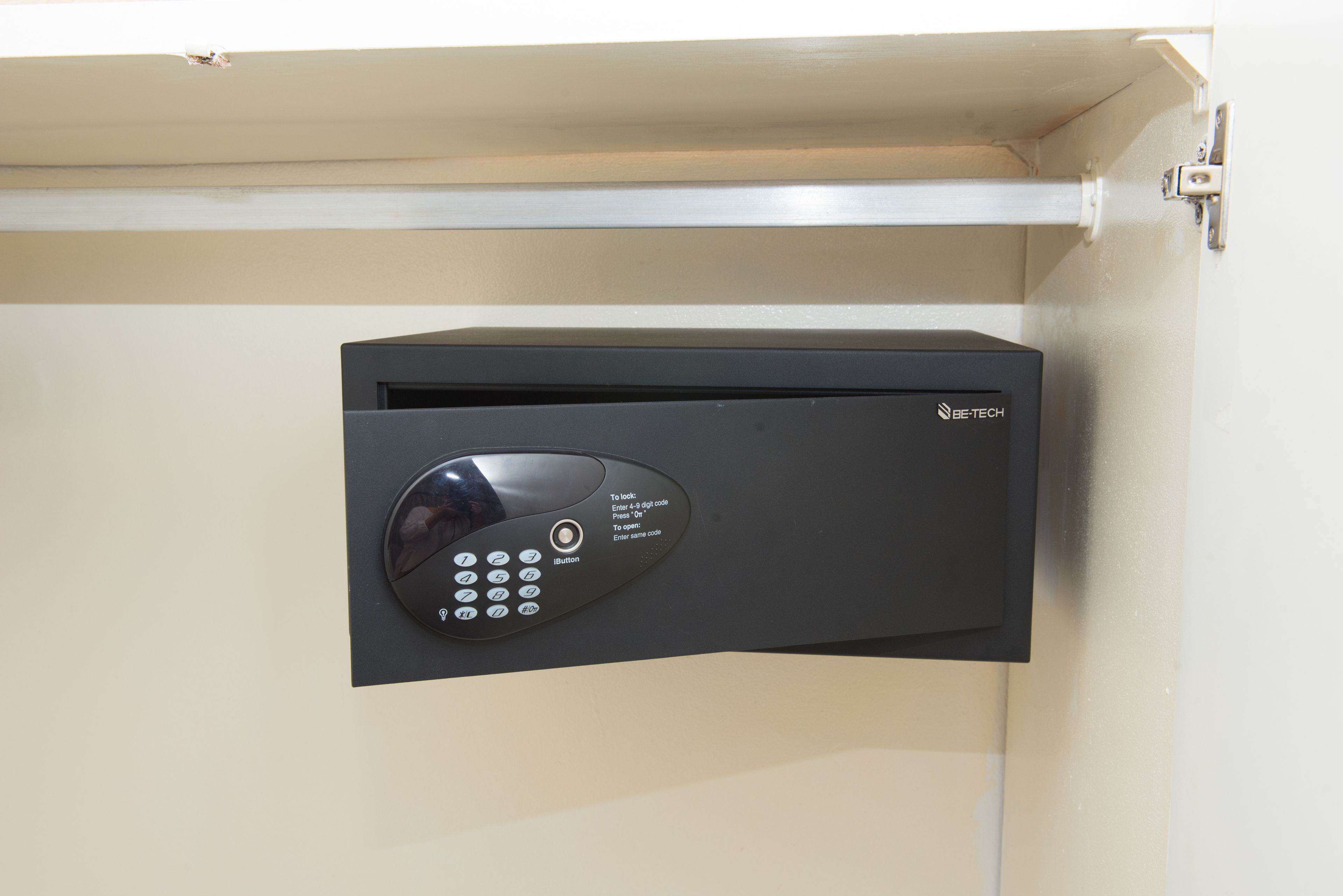 A black electronic keypad with instructions for use, mounted on a beige wall.