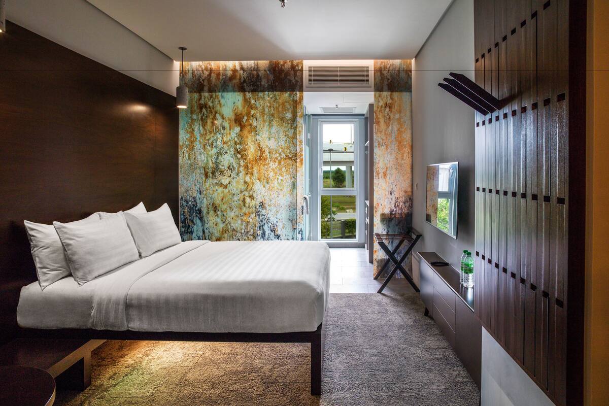 A modern bedroom with a large bed, a view to the outside, and a built-in wardrobe.