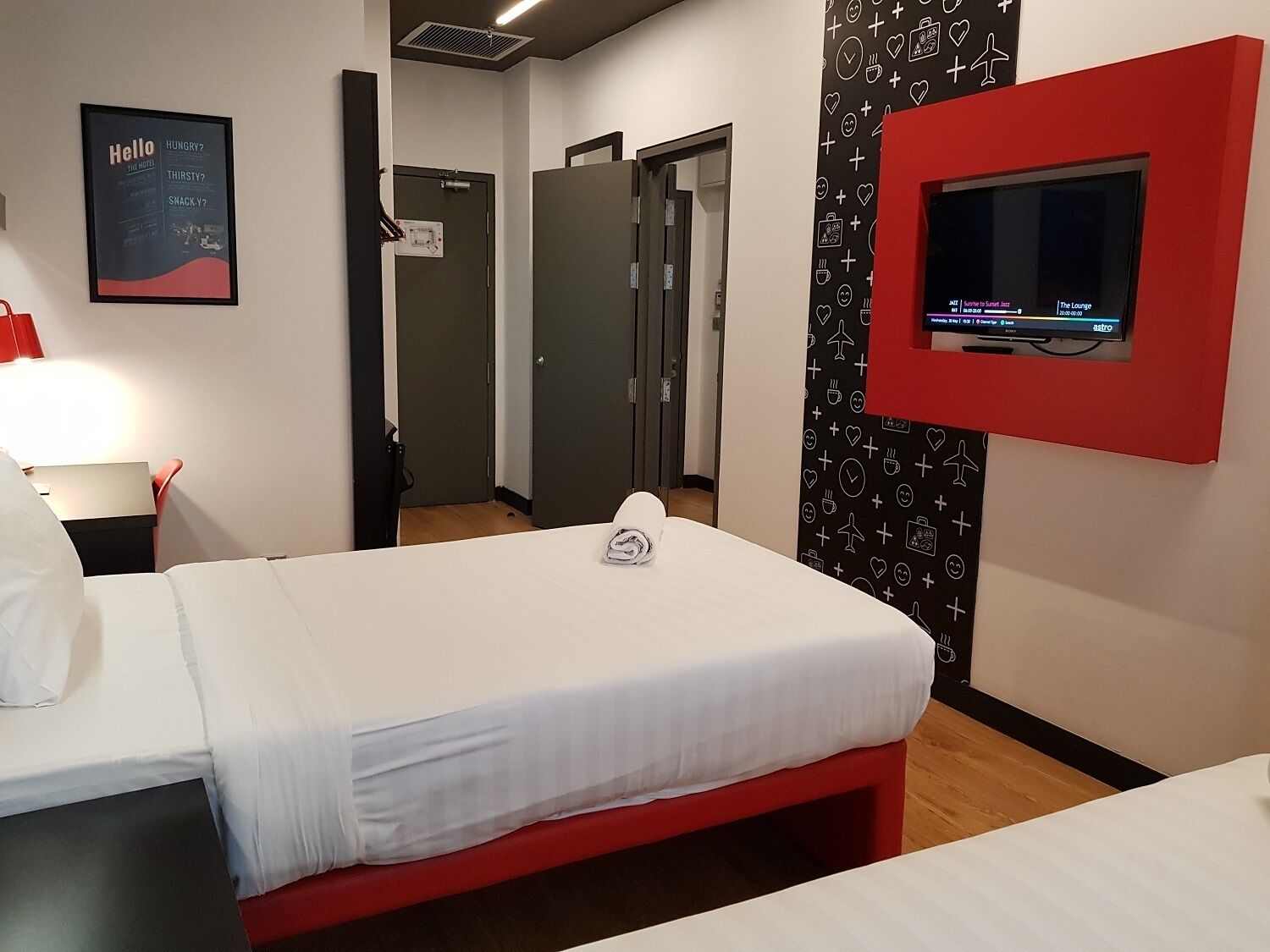 Una habitación de hotel con una cama, un televisor montado en la pared y un cartel en la pared.