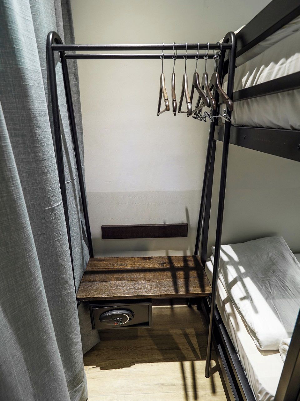 A bunk bed with a pull-out desk and a hanging rack.