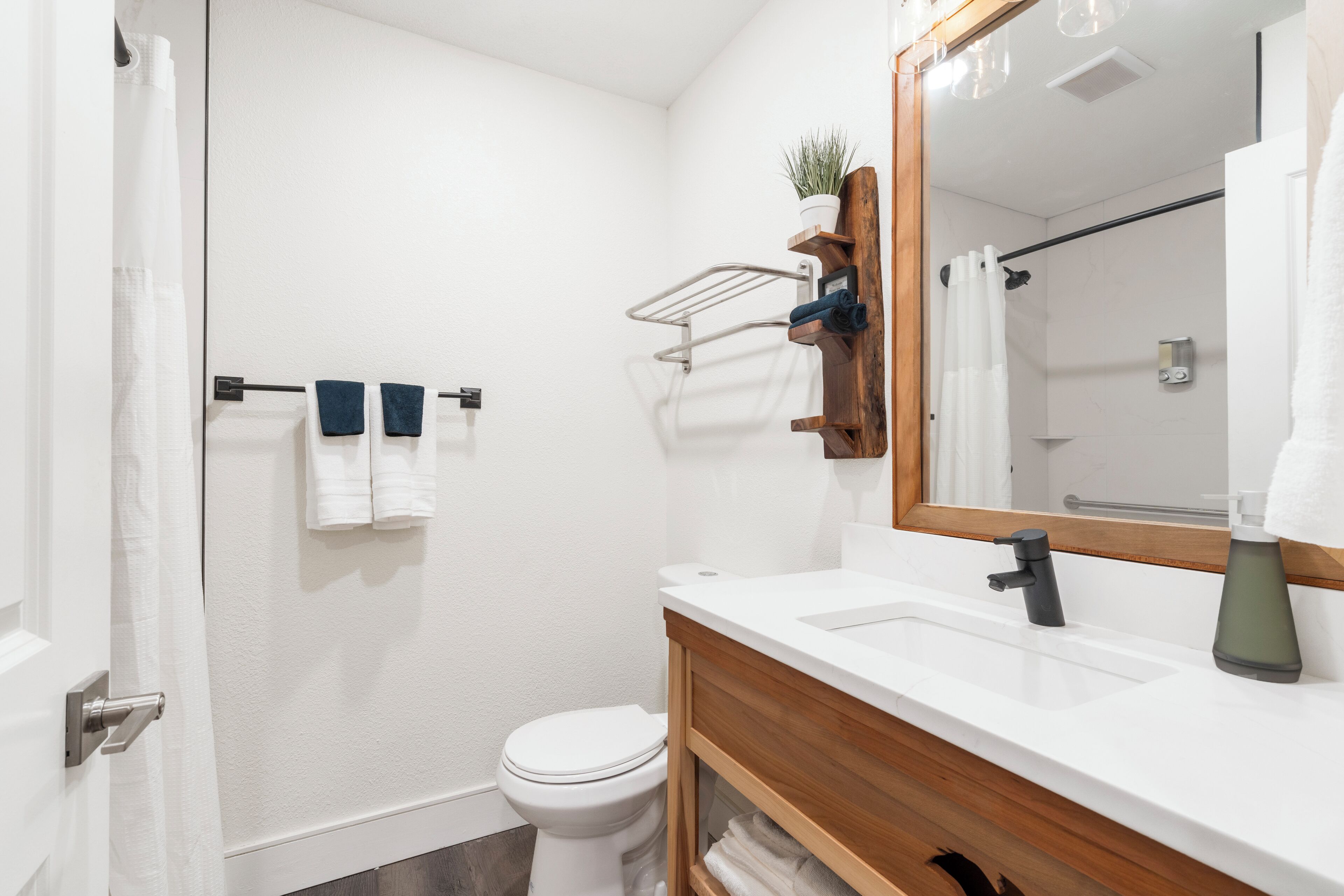 Een moderne badkamer met een wit toilet, een houten wastafelmeubel met een wastafel en een grote spiegel.