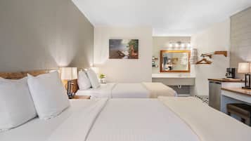 A hotel room with two beds, a bathroom with a mirror and towel rack, and a small kitchenette area.