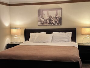 A hotel room with a large bed, two bedside tables with lamps, a framed picture on the wall, and a brown headboard. - Maxwelton Braes Lodge and Golf Course (Baileys Harbor)