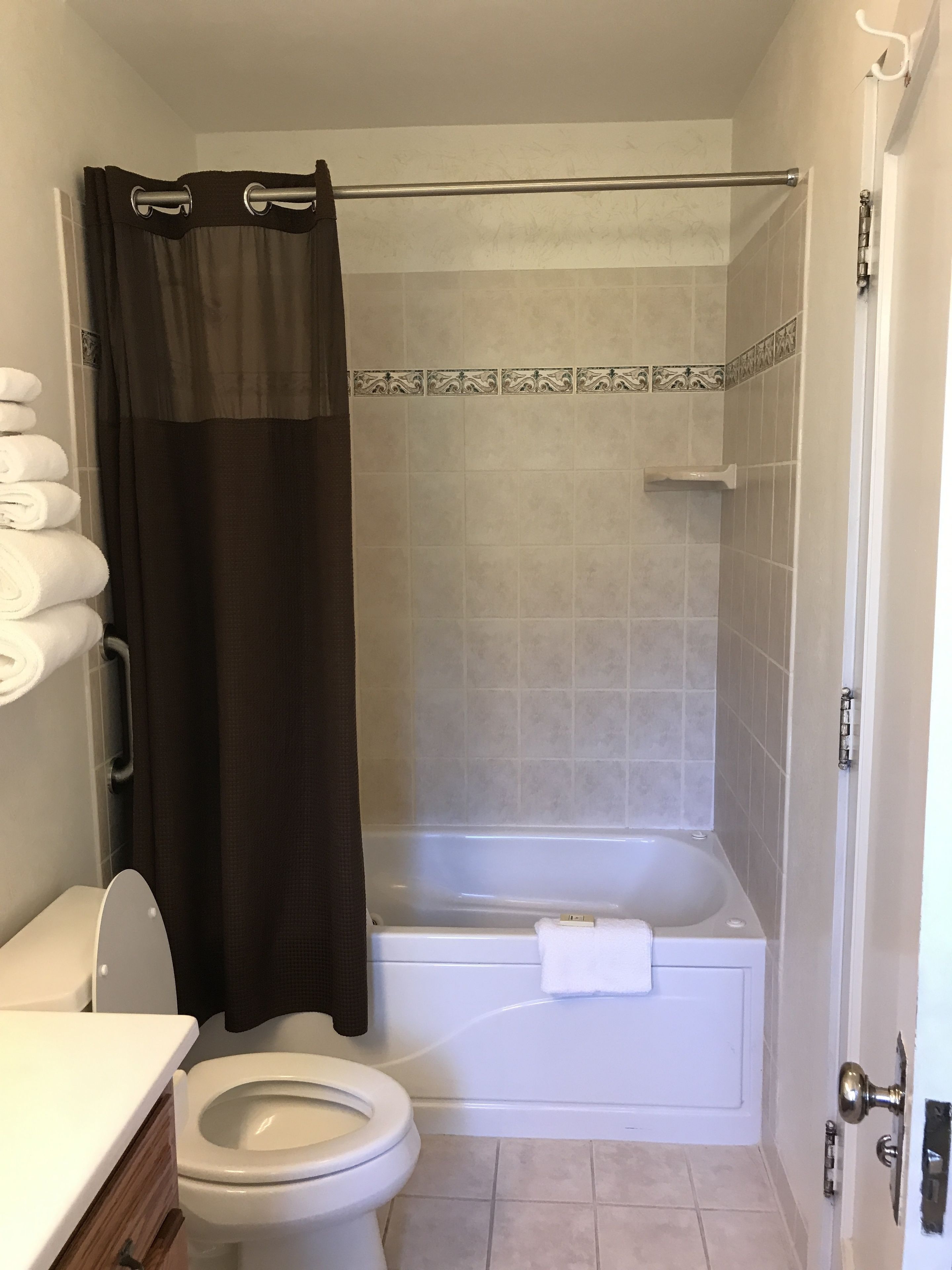 Une salle de bain équipée de toilettes, d’une baignoire et d’un rideau de douche.