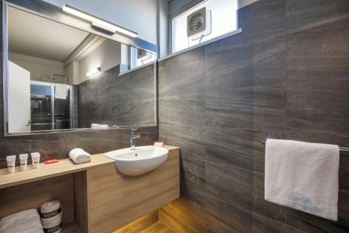 A modern bathroom with a large mirror, a sink, and a towel rack.