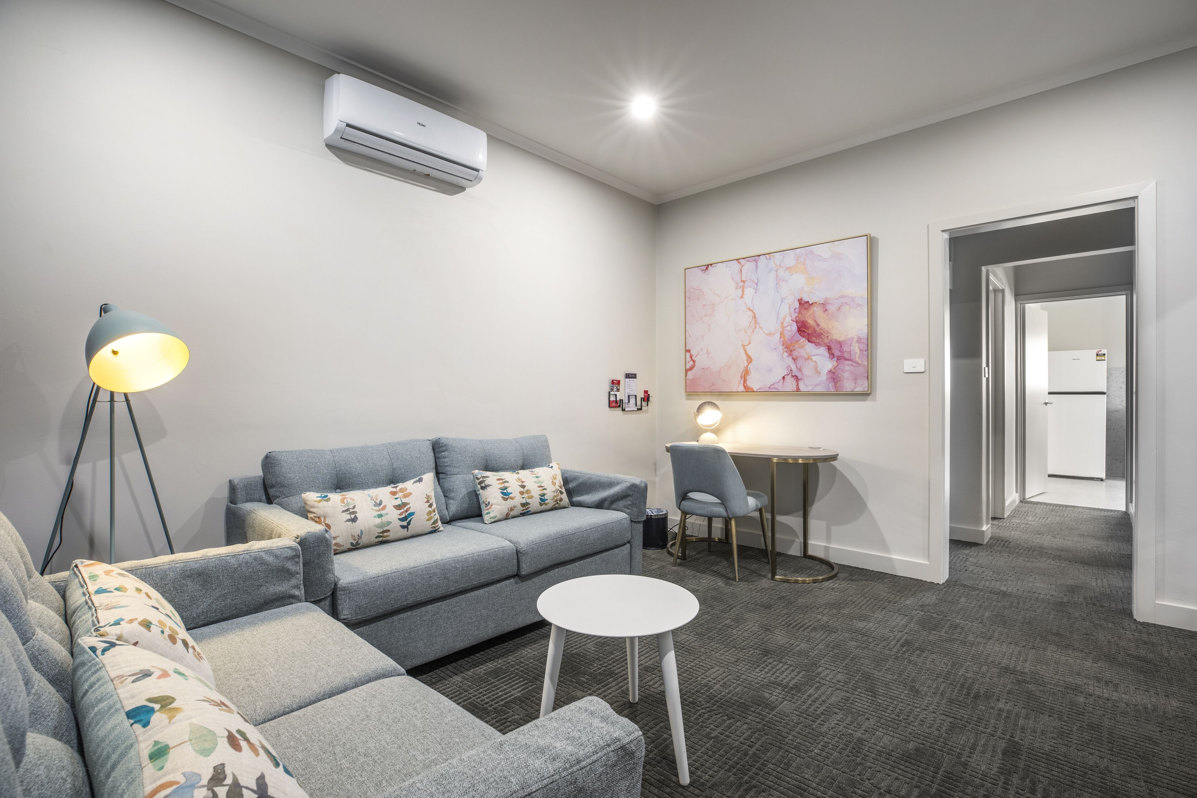 A modern living room with a grey sofa, a small round table, and a lamp.