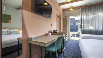 Een hotelkamer met een bed, een bureau met stoel, een televisie en een deur die leidt naar een balkon.