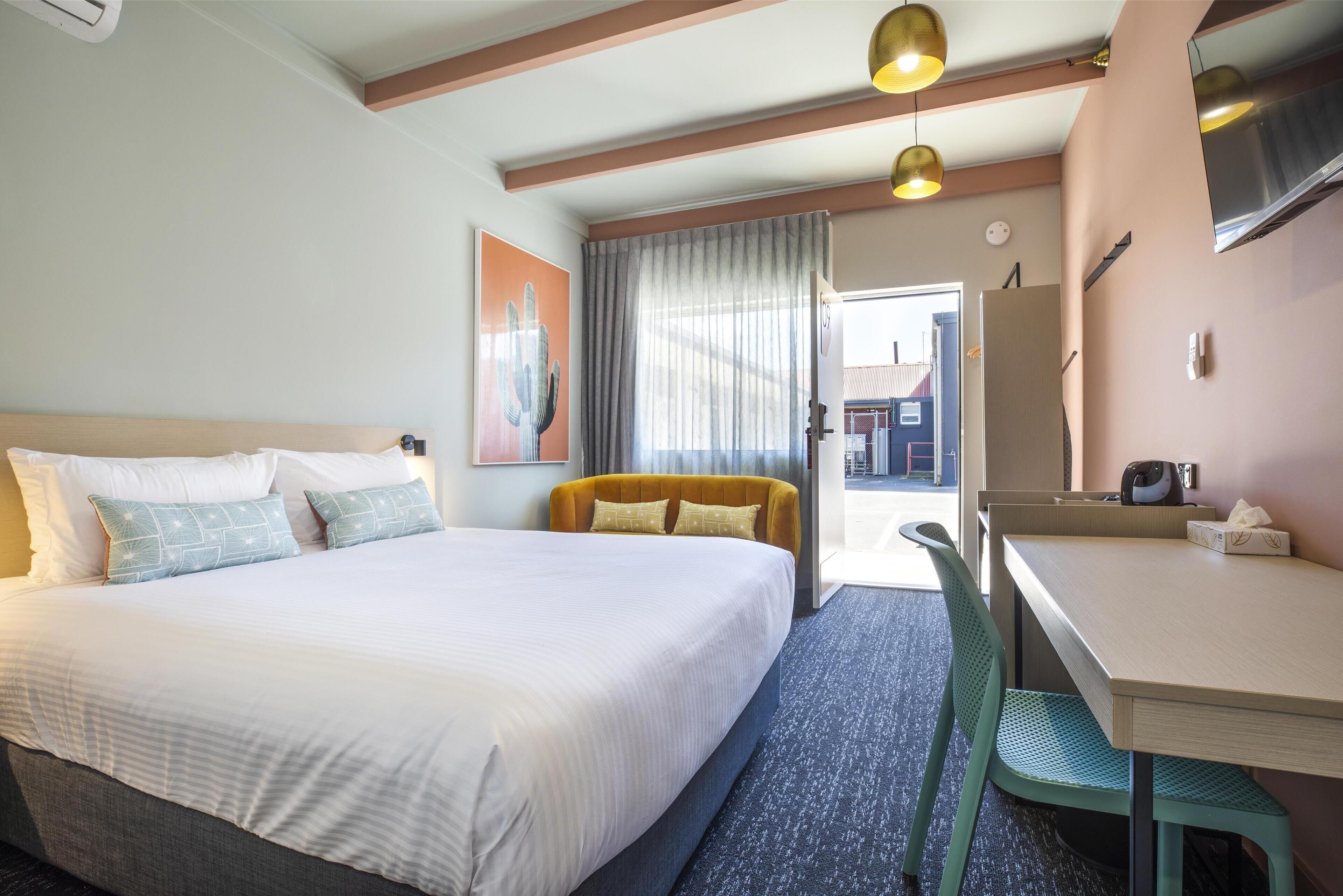 Une chambre d’hôtel avec un grand lit, un bureau, une chaise et une vue sur l’extérieur.