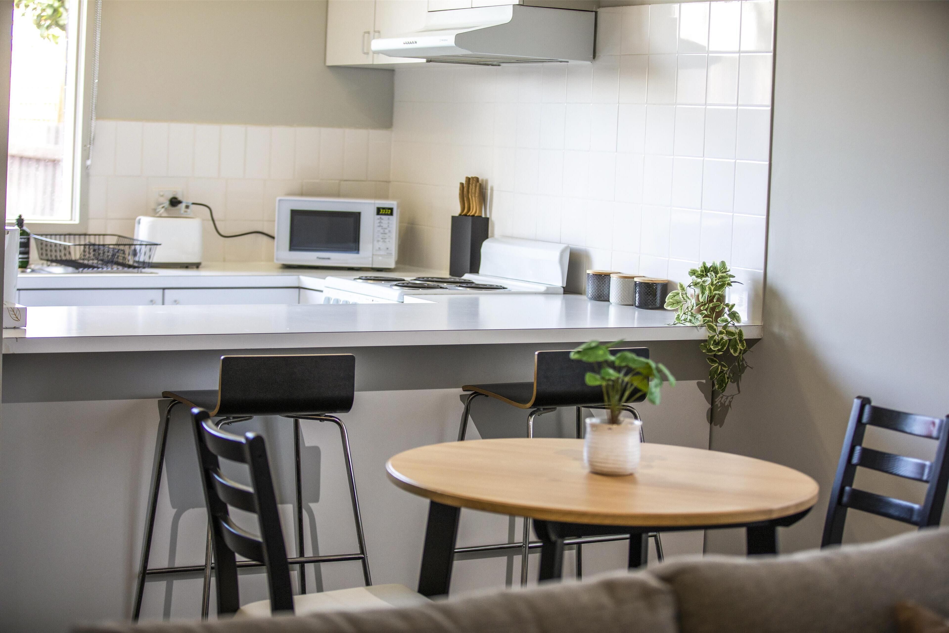 A modern kitchen with a microwave, toaster, and a potted plant on the counter.