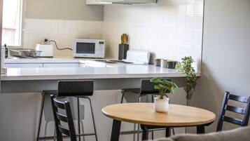 A modern kitchen with a microwave, toaster, and a potted plant on the counter.