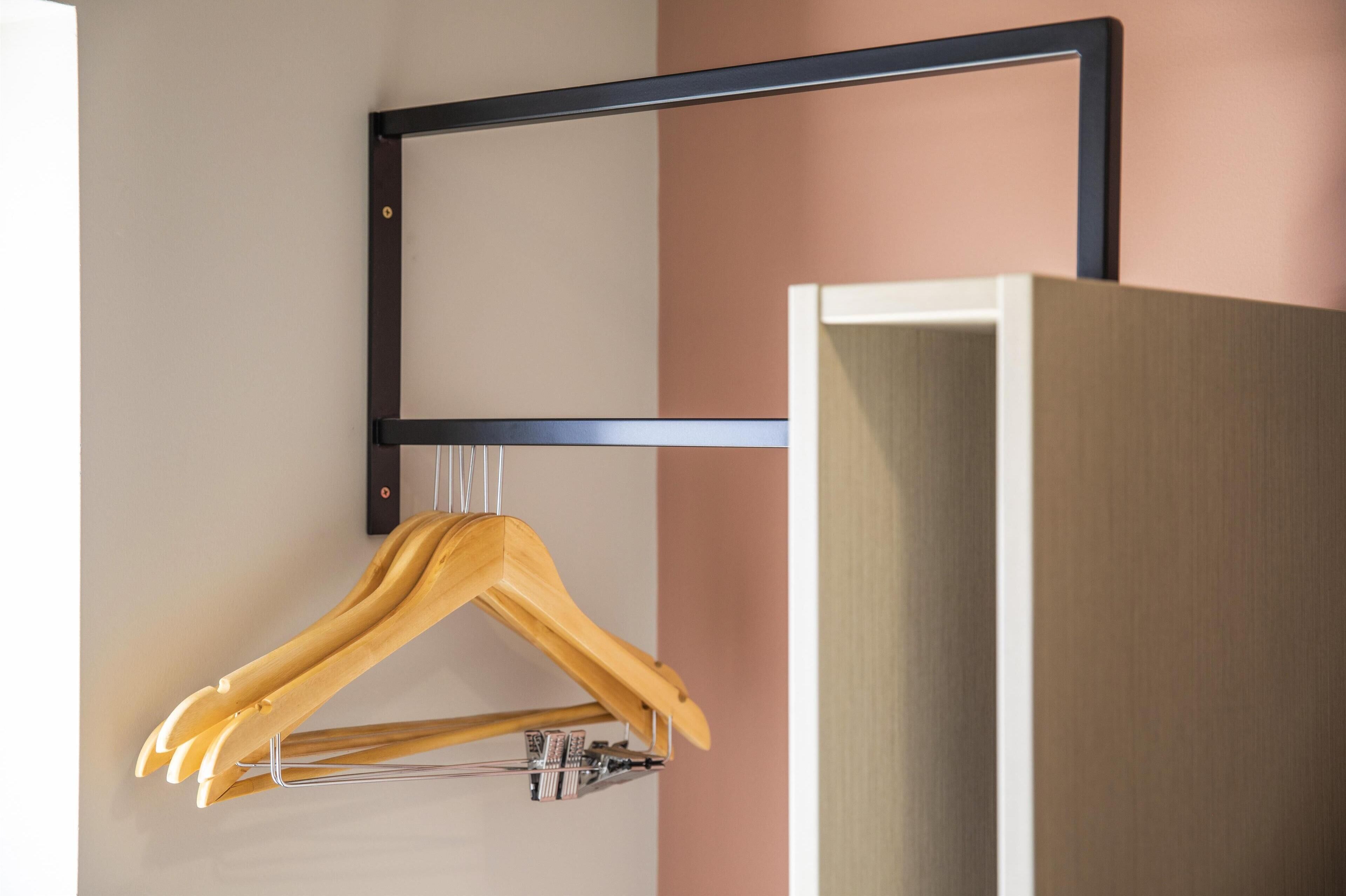 A wooden hanger on a metal rack against a wall with a wooden cabinet.