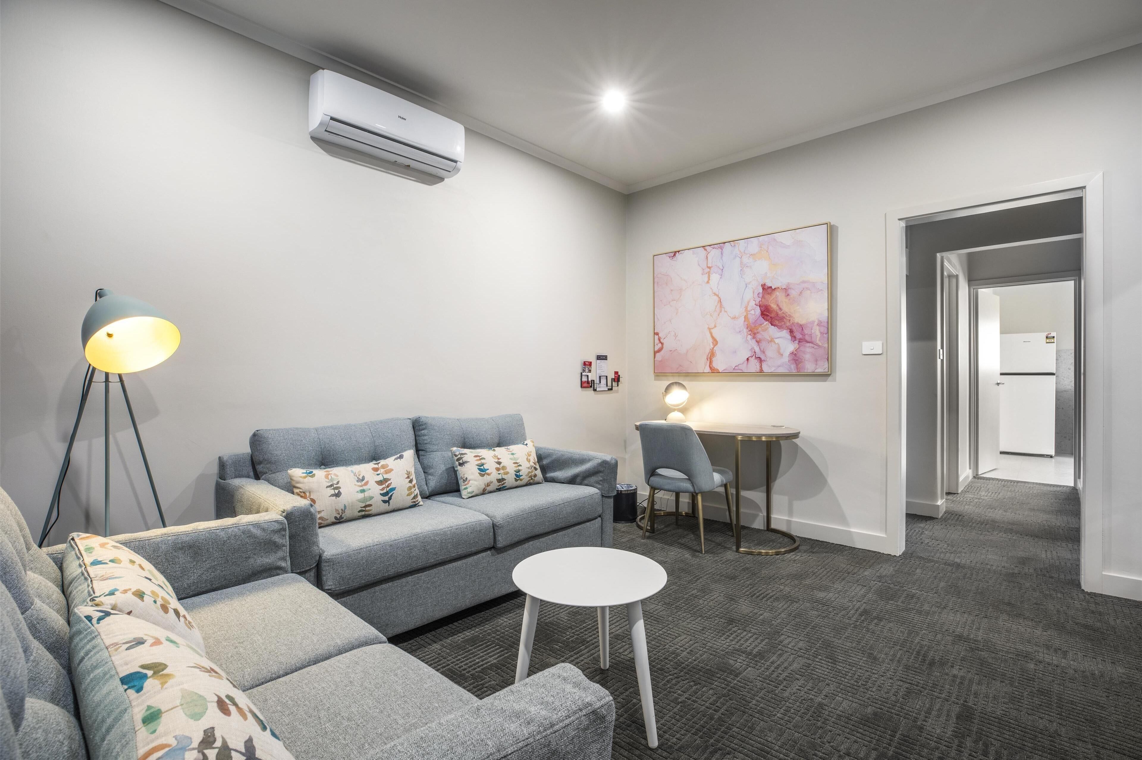 A modern living room with a grey sofa, a small round table, and a floor lamp.