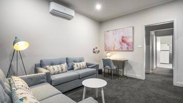 A modern living room with a grey sofa, a small round table, and a floor lamp.