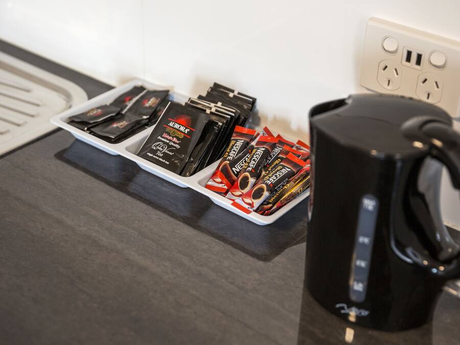A countertop with a black coffee maker, a tray of coffee pods, and a power outlet.
