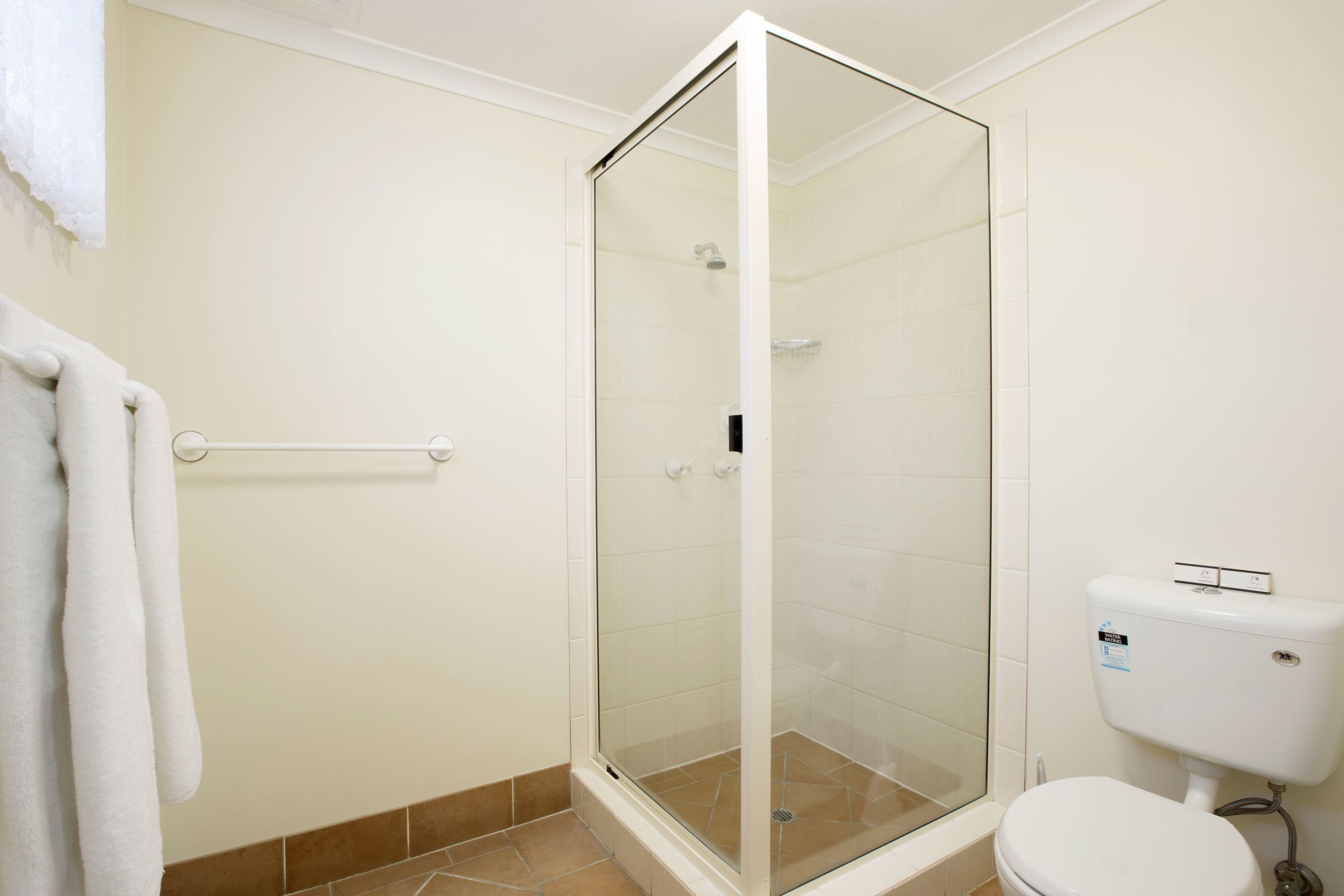 Ein Badezimmer mit Duschkabine, weißer Toilette und Handtuchhalter.