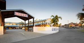 A motel with a covered entrance, a parking area, and a building with a 'red' sign.