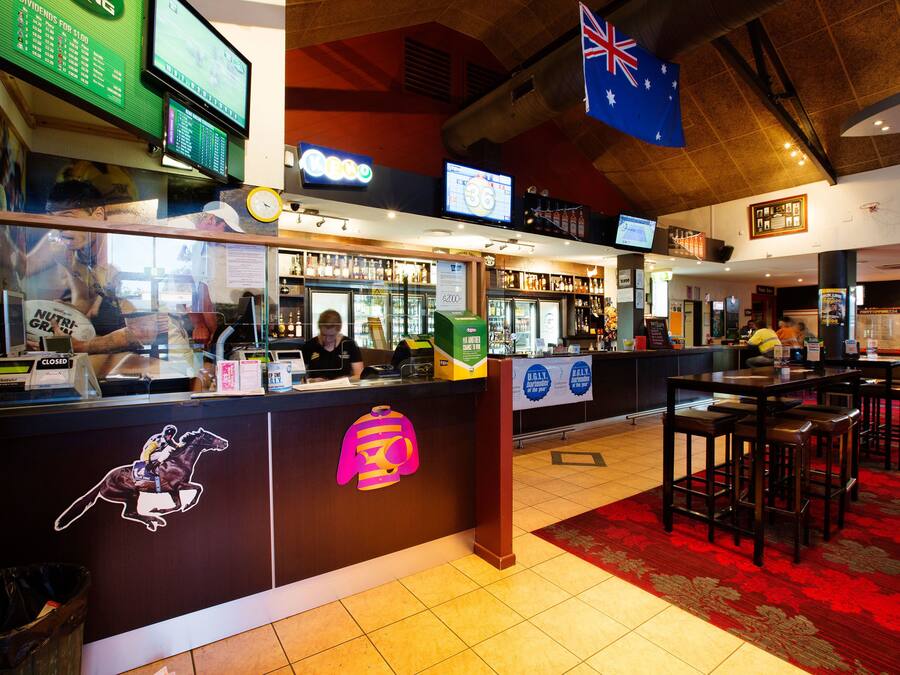 A bar area with a counter, stools, and a red carpet.