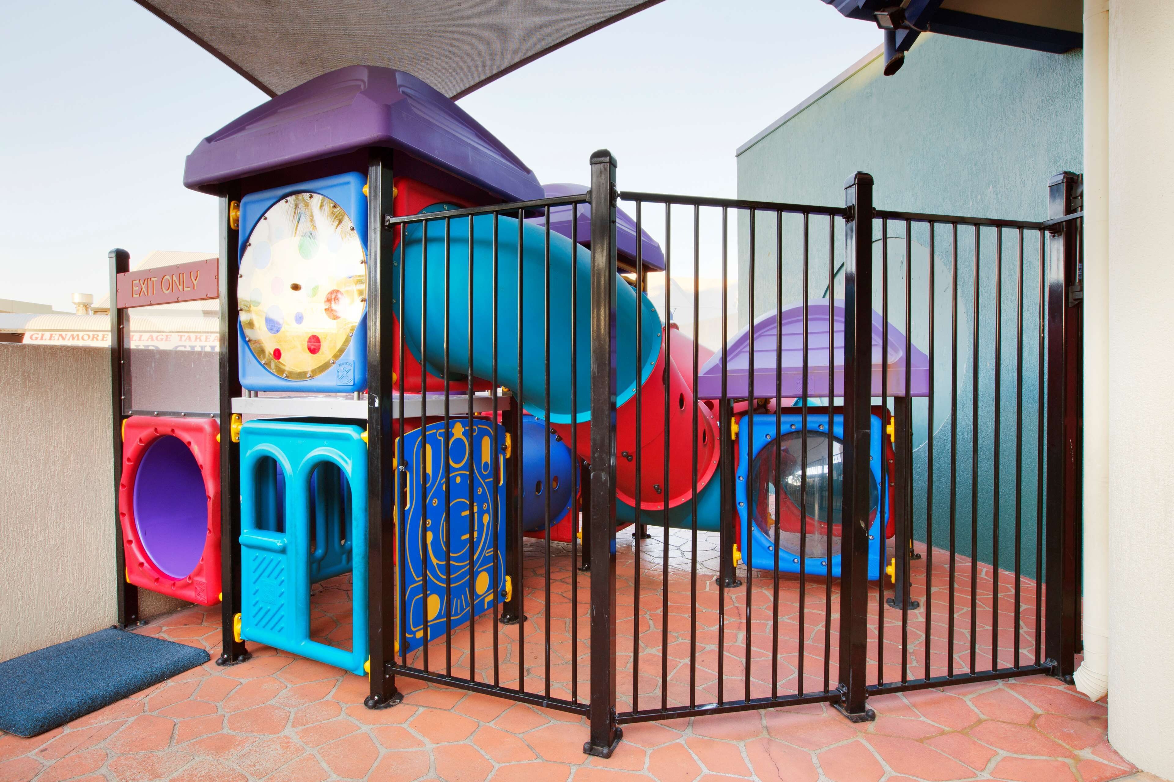 A playground with a slide, climbing structures, and a fenced area.