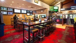 A bar area with multiple screens displaying sports content, a bar counter, and stools. - Glenmore Tavern (Norman Gardens)