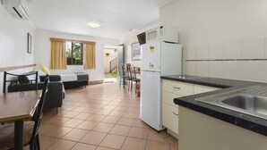 A compact kitchen with a refrigerator, microwave, and sink. There is a dining area with a table and chairs. - Glenmore Tavern (Norman Gardens)