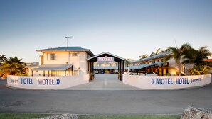 A motel with a central entrance, multiple buildings, and a well-maintained lawn. - Glenmore Tavern (Norman Gardens)