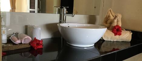 Un baño con un lavabo blanco, un espejo, una toalla y artículos de aseo en la encimera.