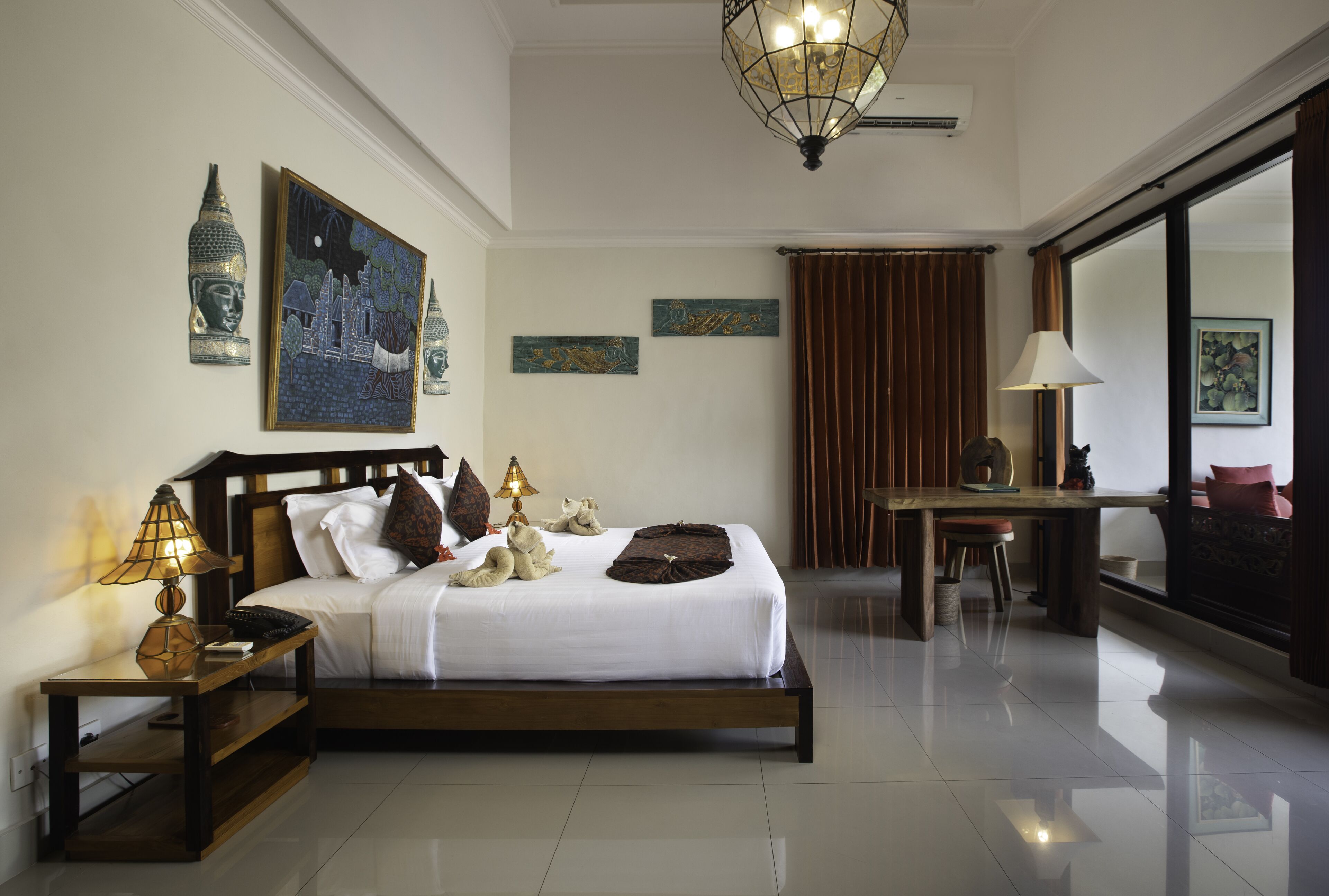 A well-lit hotel room with a large bed, a desk, and a mirror.