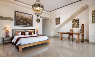 A modern bedroom with a large bed, a desk, and a chandelier.