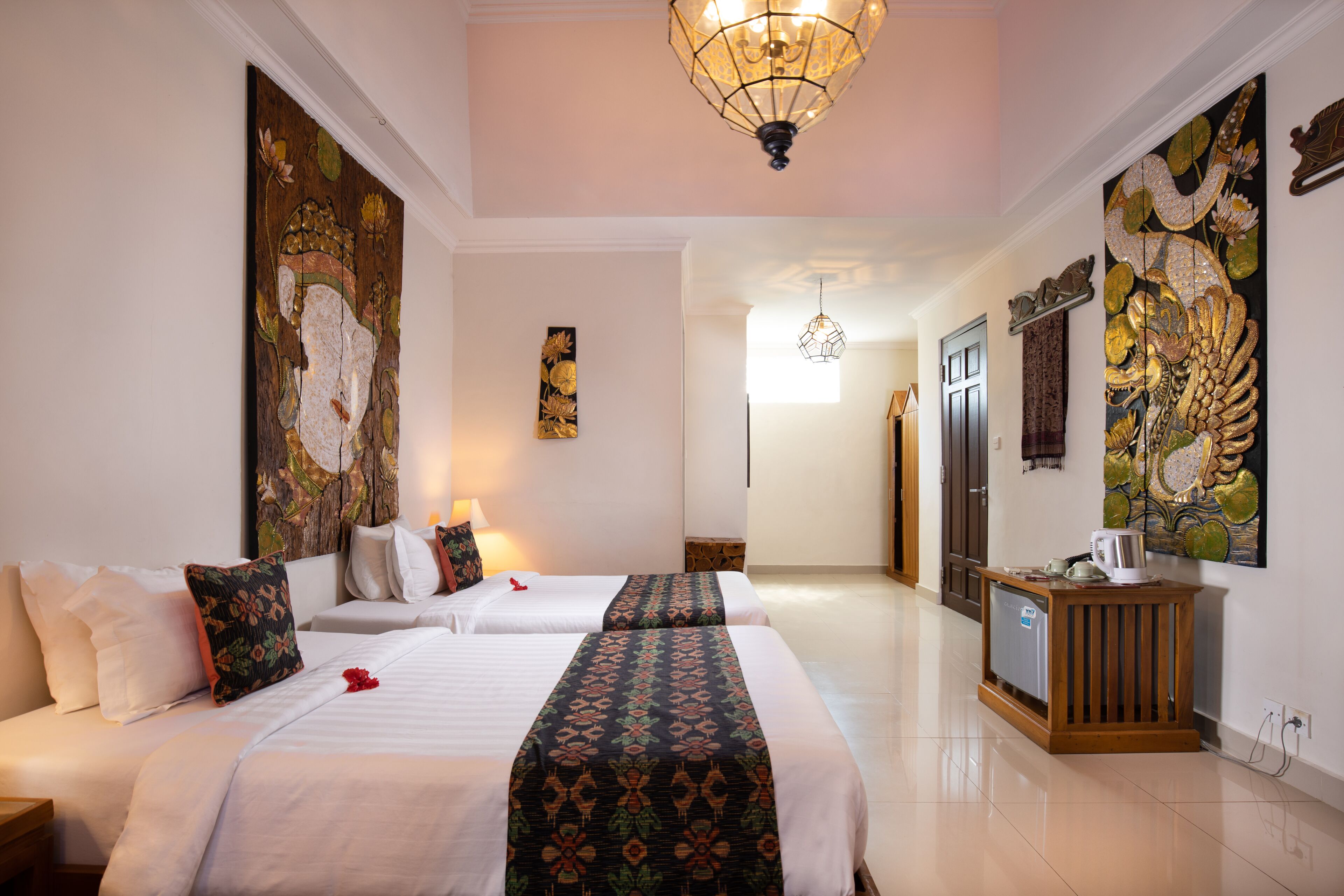A hotel room with two beds, a wooden cabinet, and artwork on the walls.