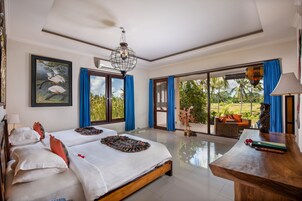 A spacious bedroom with a large bed, a wooden desk, and a view of the outdoors.