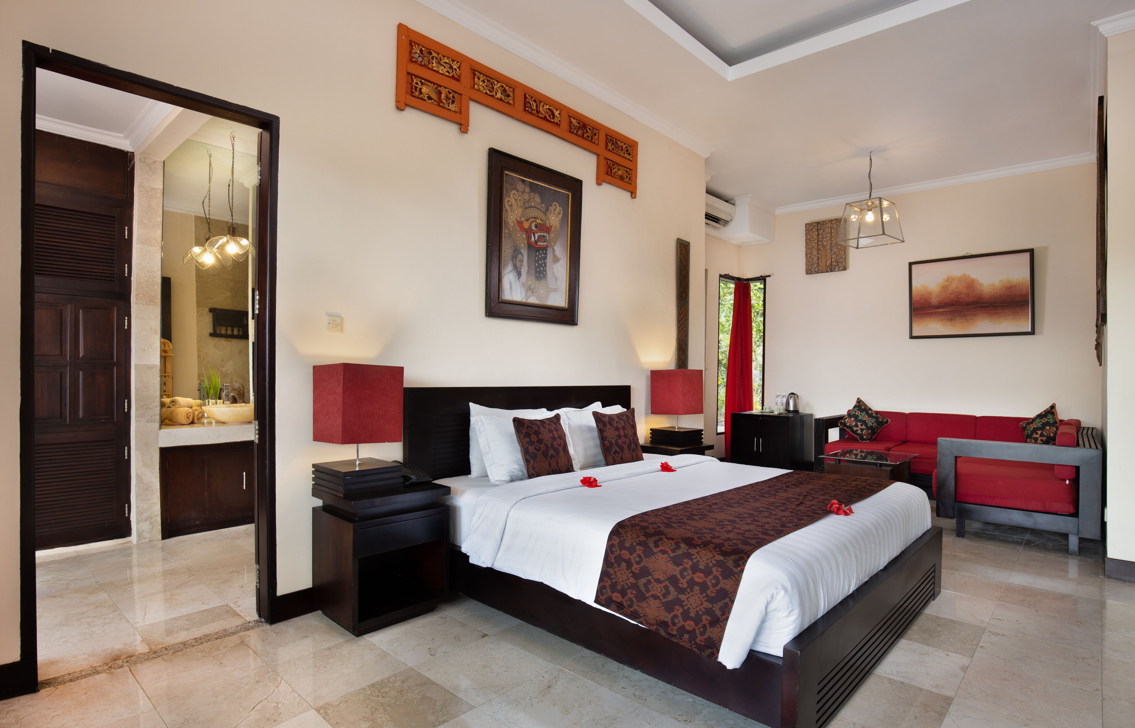 Habitación de hotel con una cama grande, un sofá rojo, un escritorio y un espejo.