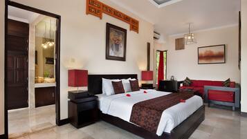Habitación de hotel con una cama grande, un sofá rojo, un escritorio y un espejo.