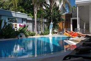 A swimming pool with a water feature, surrounded by greenery and a building with a sign that reads "SEA". - Sealife Lounge Hotel - Adult Only (Konyaalti)