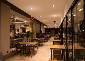 Un restaurante amplio con numerosas mesas y sillas, un diseño de interiores moderno y luces decorativas en forma de estrella en el techo.