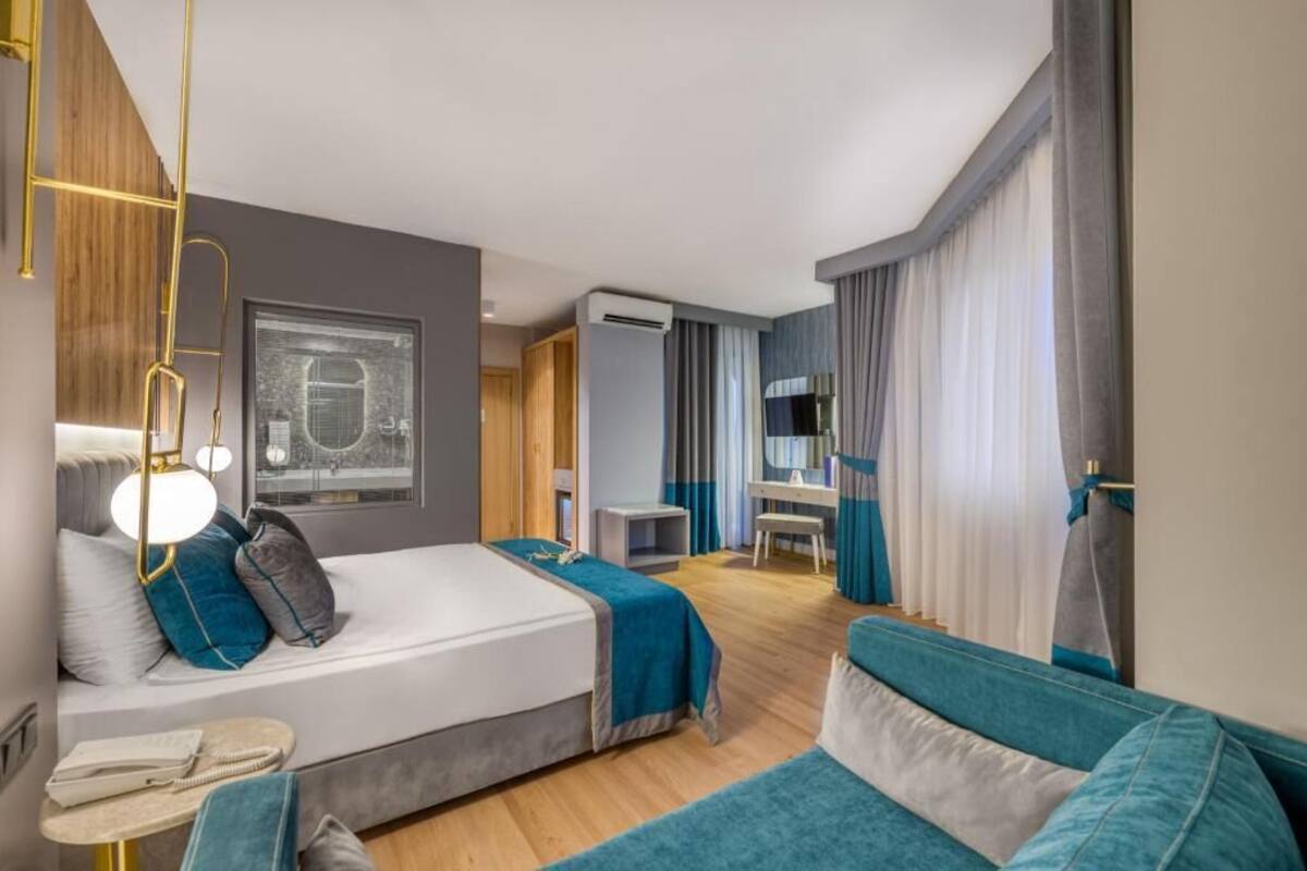 A modern hotel room with a bed, a desk, and a seating area.