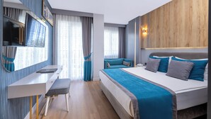 A modern hotel room with a bed, a desk, a TV, and a window with curtains.