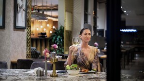 A dining area with a marble table, a bowl of salad, and a glass of wine.