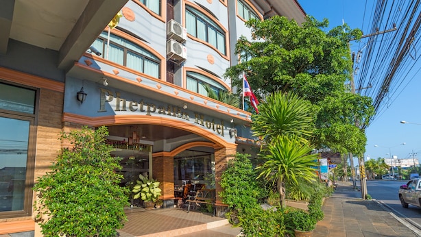Entrada de un hotel con fachada curva, ventanas grandes y una bandera.