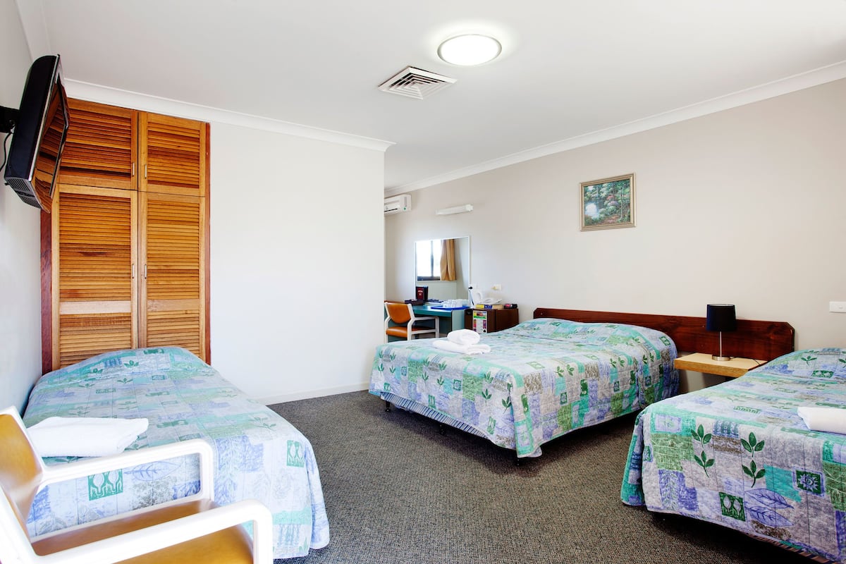 A hotel room with two beds, a desk, a chair, a TV, and a wardrobe.