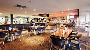 A spacious restaurant with multiple tables and chairs, a bar area, and a counter with a menu. - Vale Hotel (Aitkenvale)