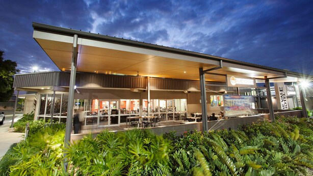 A modern hotel with an outdoor seating area and a covered patio. - Vale Hotel (Aitkenvale)